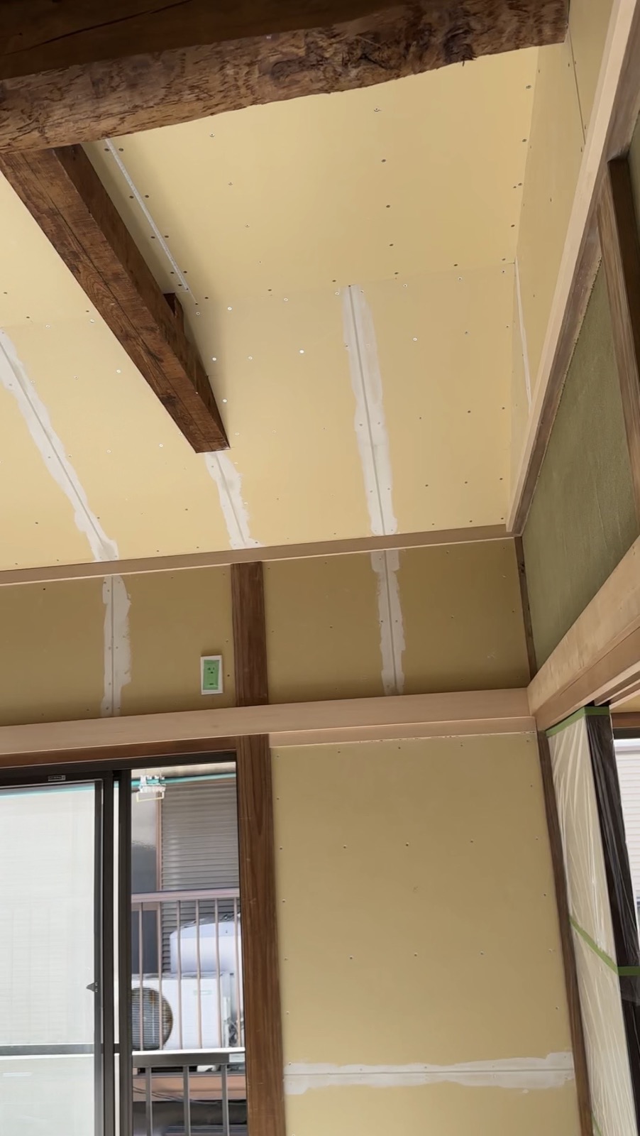 Ceiling drywall with exposed wooden beams during akiya finishing