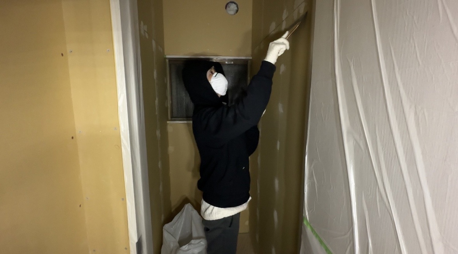 Plastering ceiling in protective suit during akiya restoration