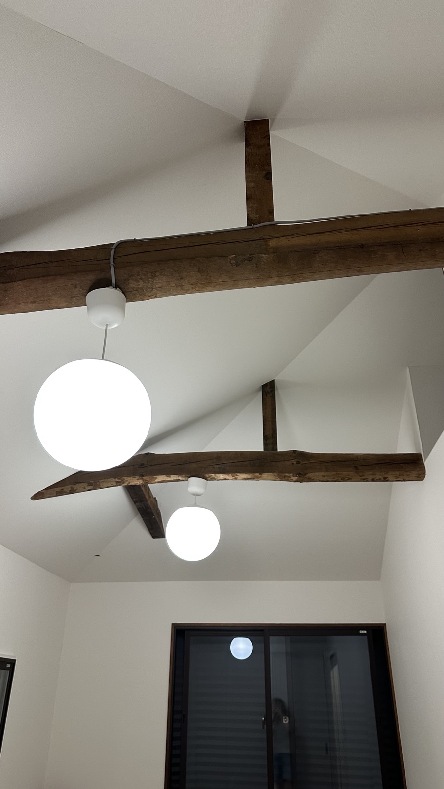 Exposed wooden beams with globe pendant lights in restored akiya ceiling